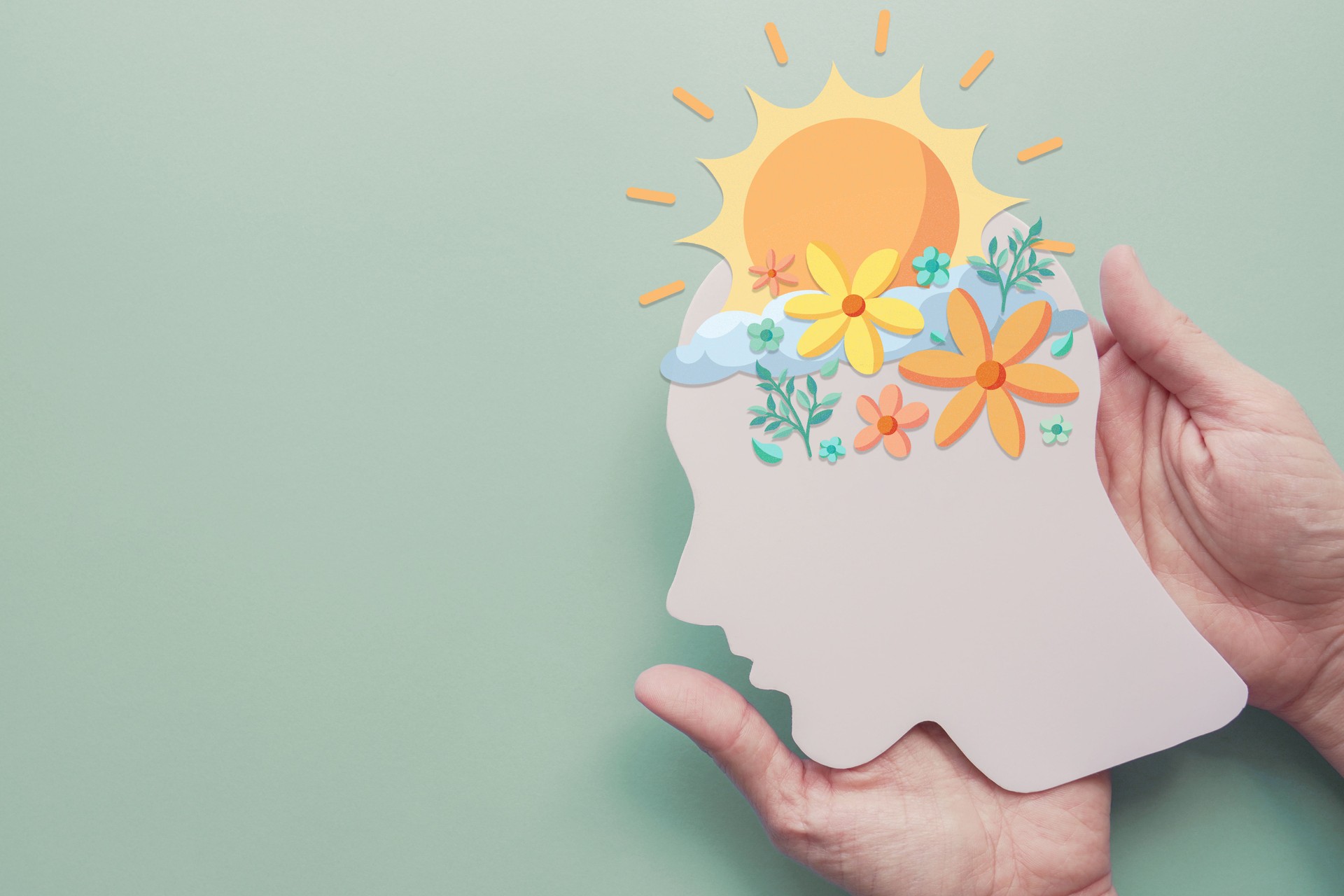 Hands holding paper brain with flowers and sunshine, positive mental health, mindfulness, wellness, self care concept